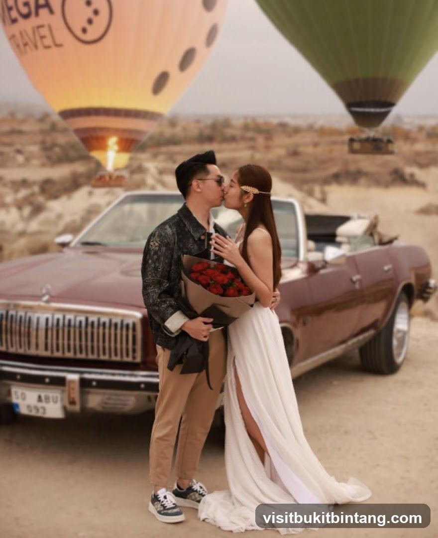 Couple kissing in front of hot air balloons and a vintage car