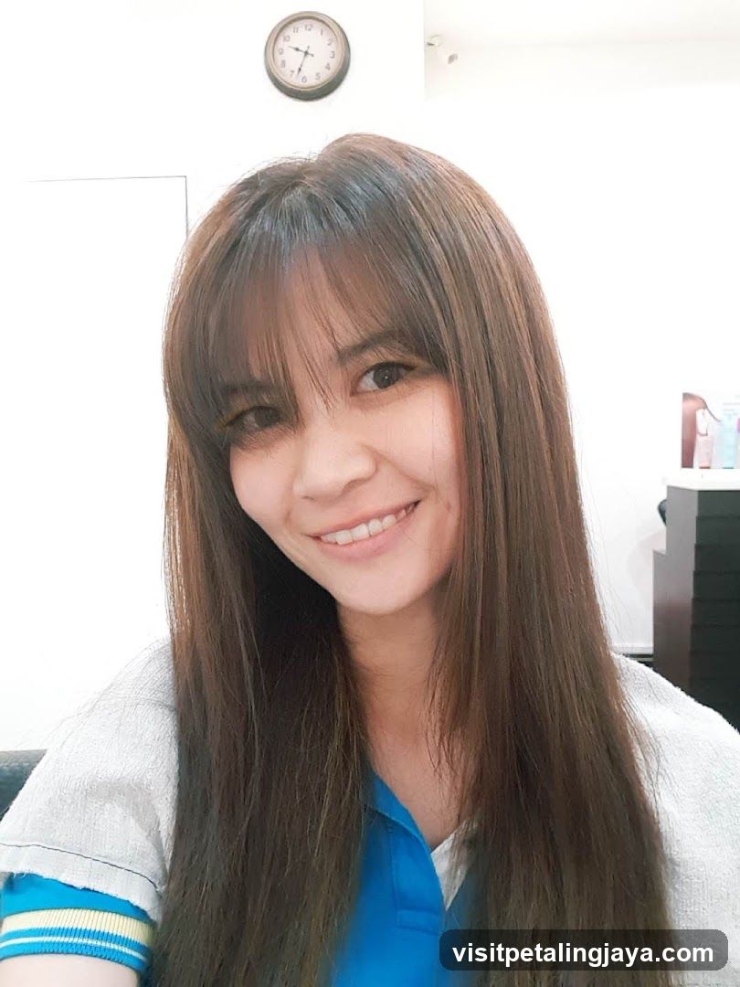 Portrait of a woman with long brown hair and bangs, smiling at the camera.