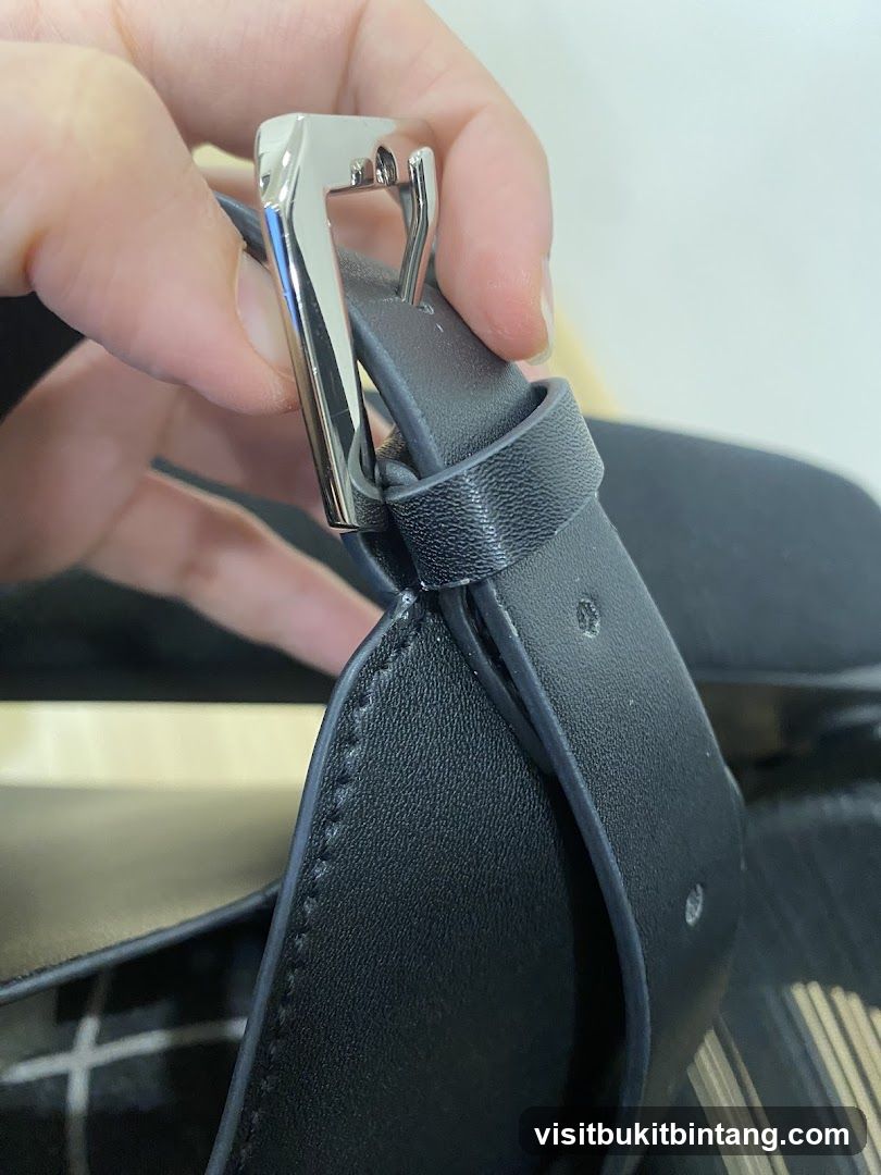 Close-up of a black leather strap with a silver buckle