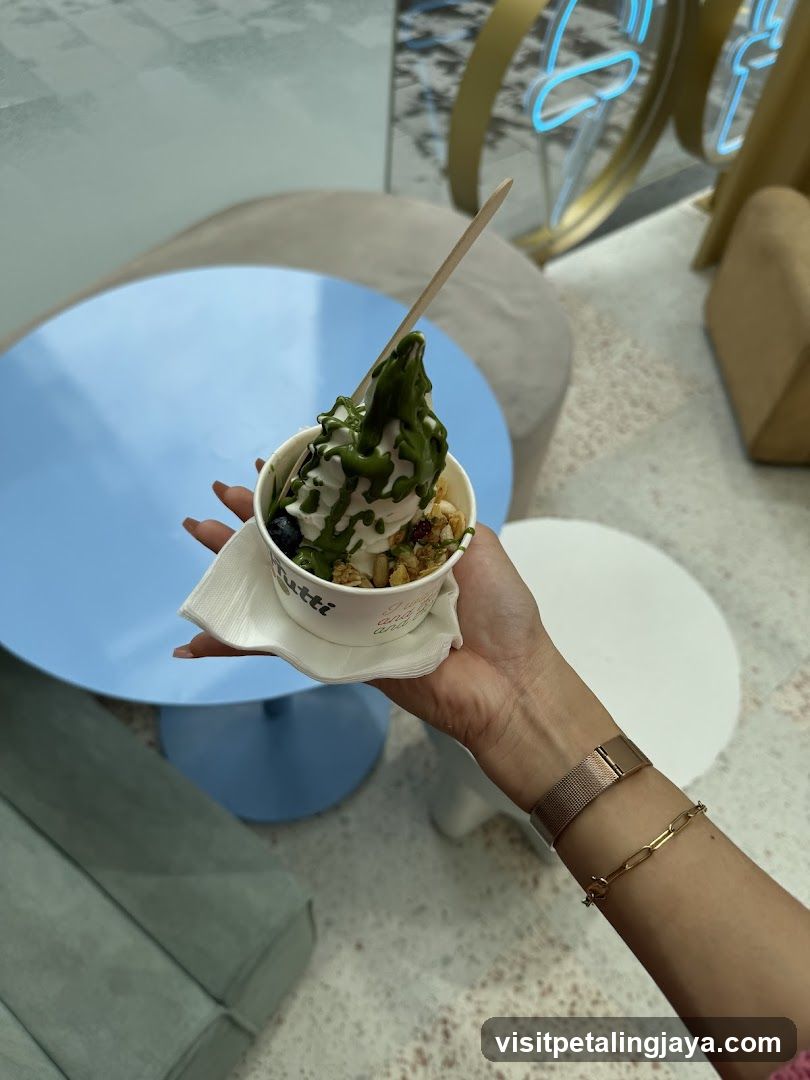 Hand holding a dessert cup with green drizzle and toppings
