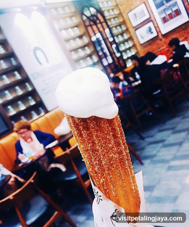 Churro with whipped cream in a cafe interior