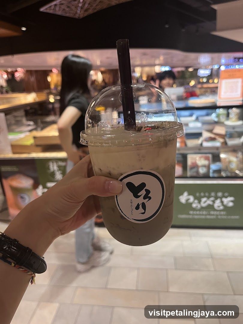 Hand holding iced coffee drink in a food court setting