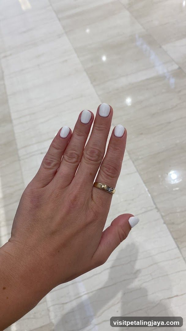 Hand with White Nail Polish and Gold Ring