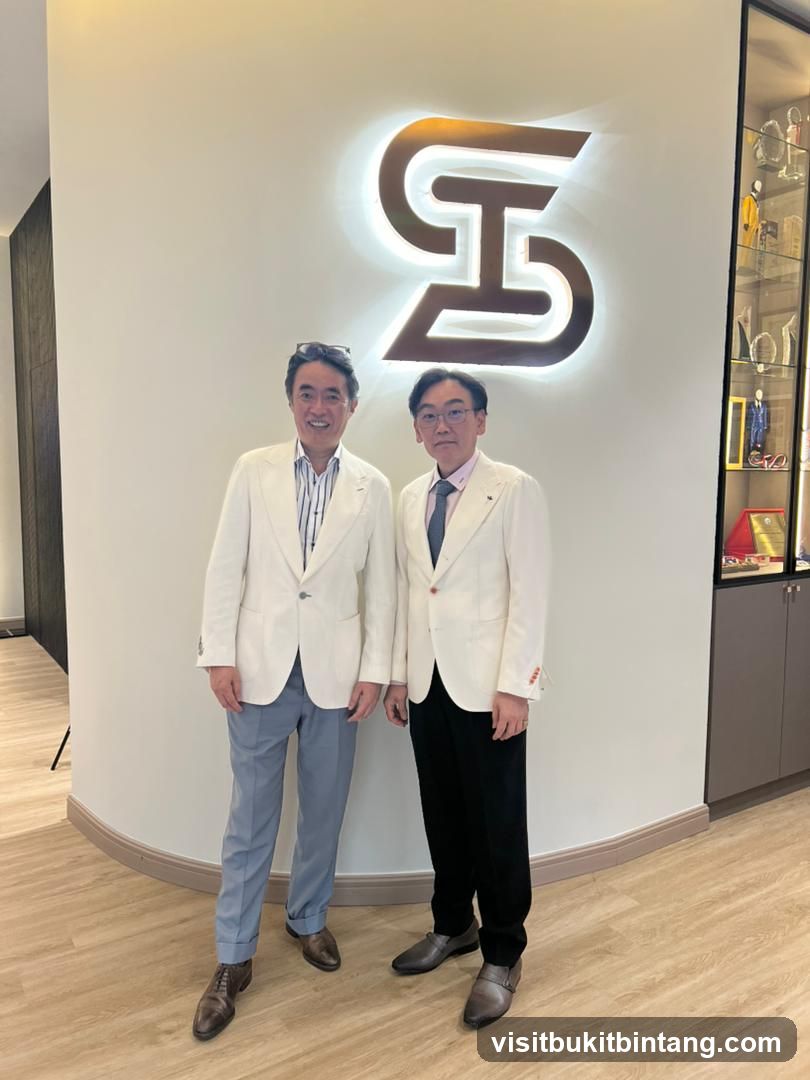 Two men in suits standing in front of a logo