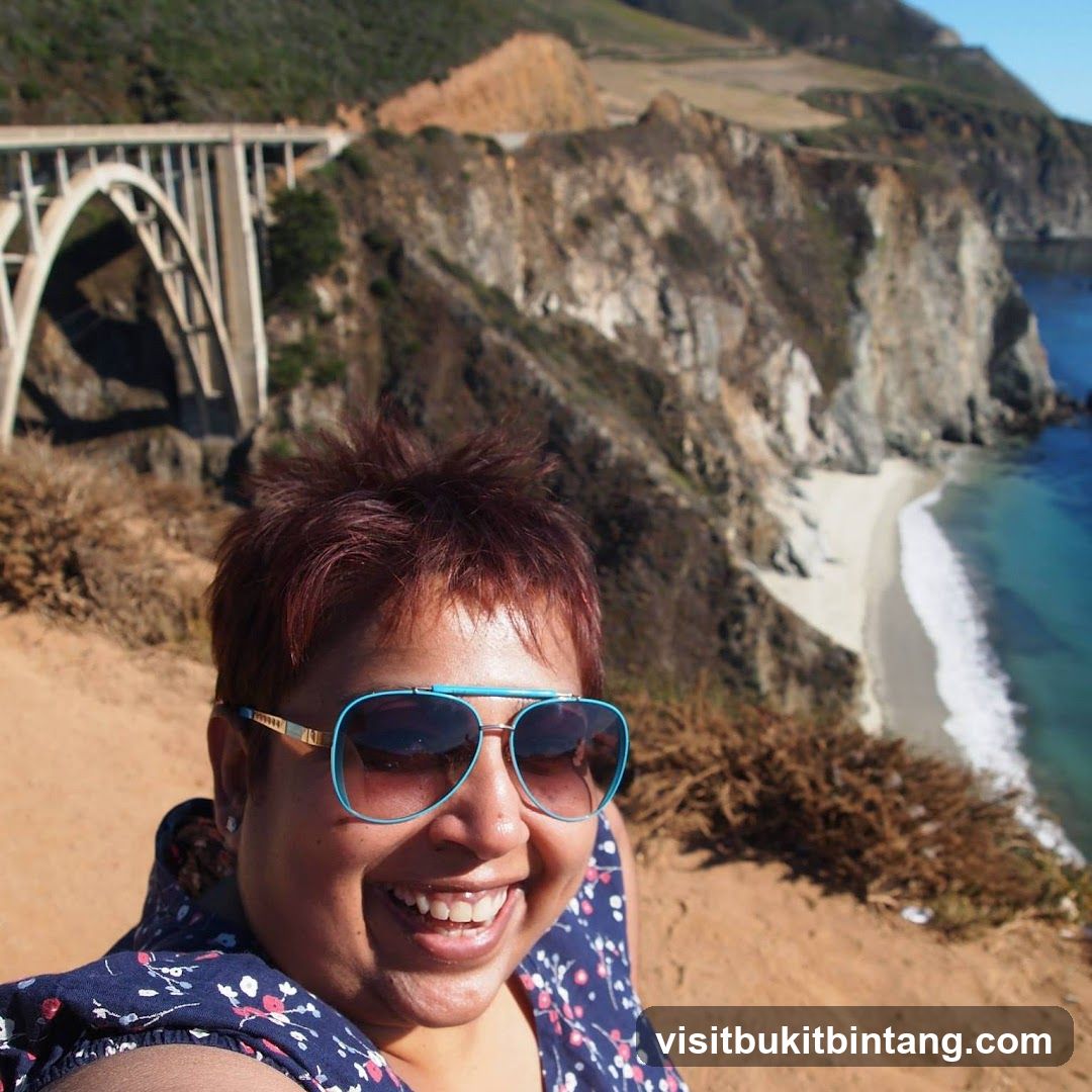 Woman smiling with sunglasses in front of a scenic coastal view