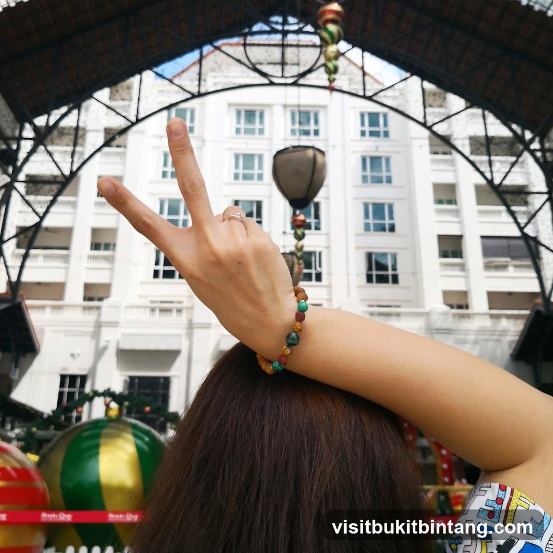 Woman making peace sign with building in background