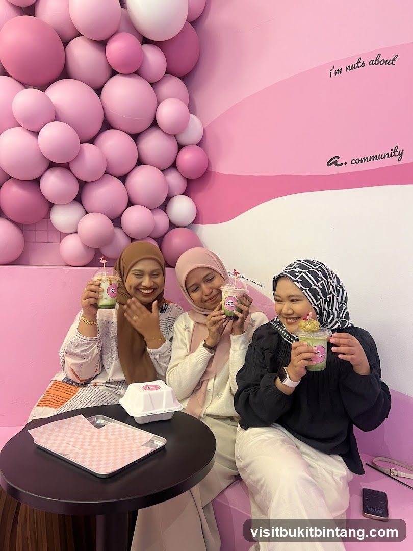 Three women enjoying drinks in a pink-themed cafe