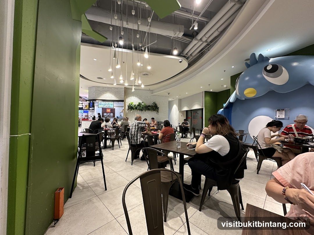 Diners in a brightly lit restaurant with a large blue cartoon character decoration