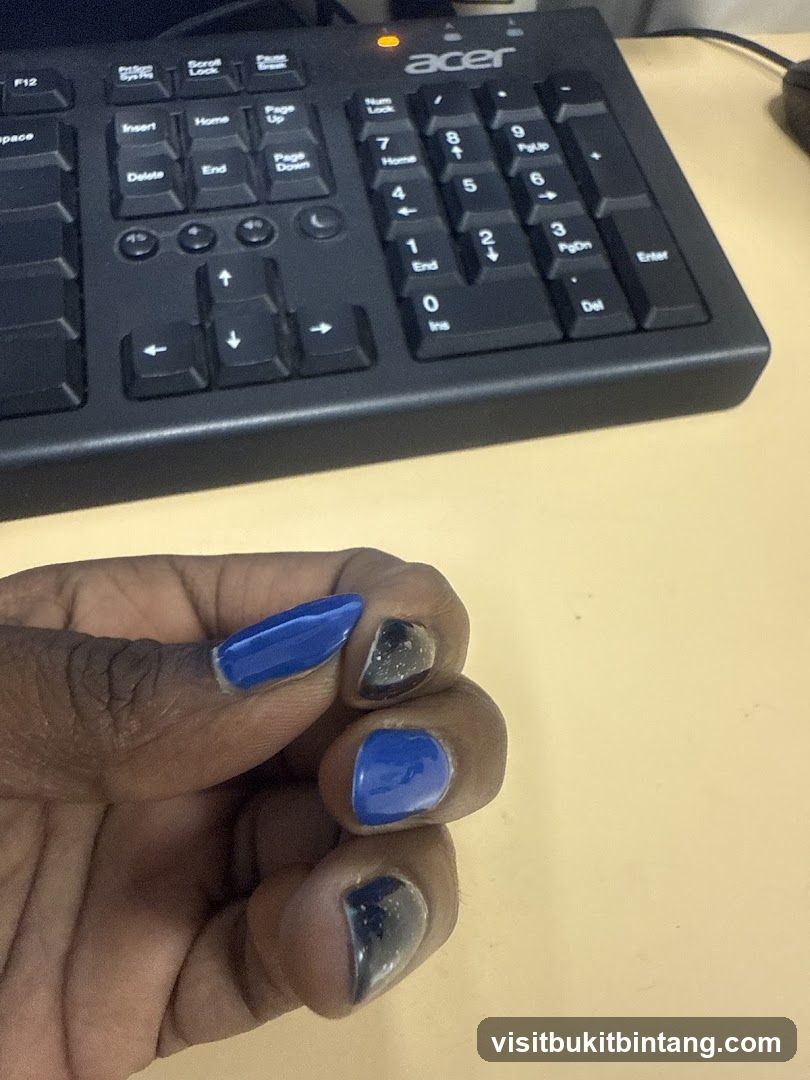 Keyboard and hand with blue and black nails