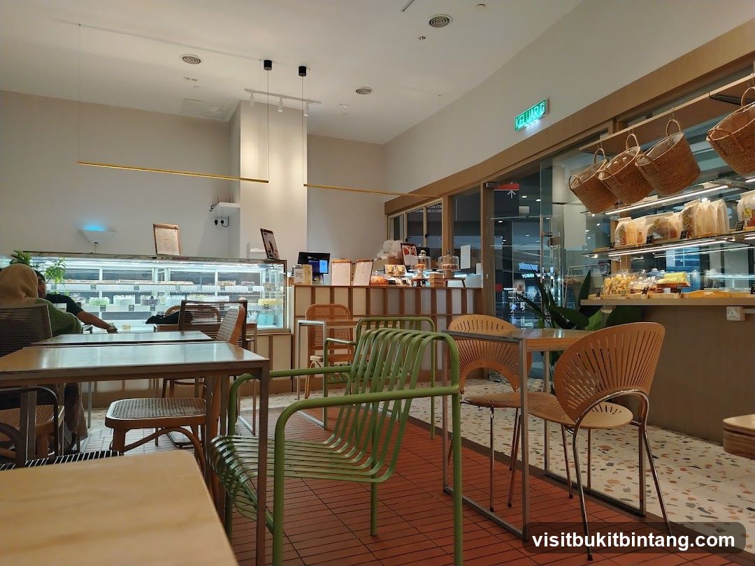 Interior of a modern cafe with display cases of pastries and seating areas.
