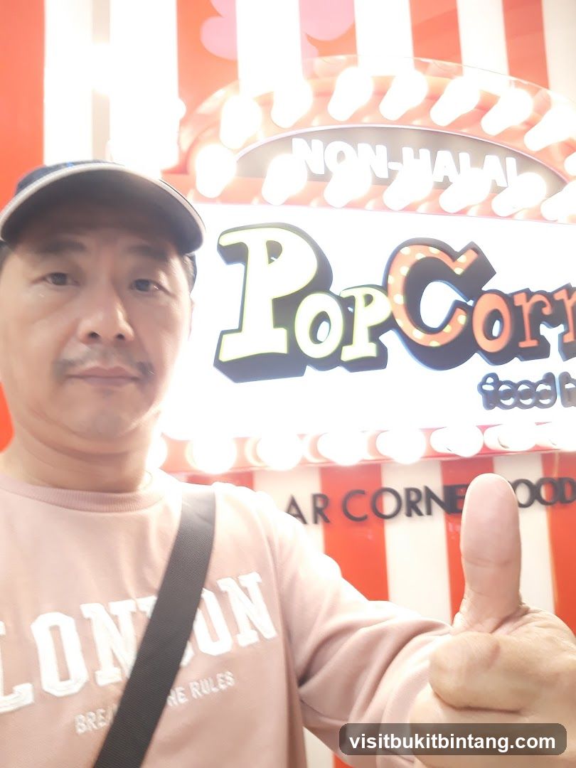 Man giving a thumbs up in front of a popcorn sign