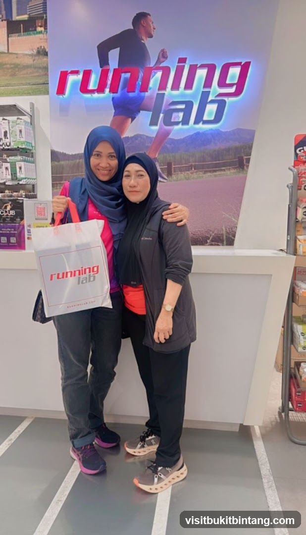 Two women posing in front of a Running Lab advertisement