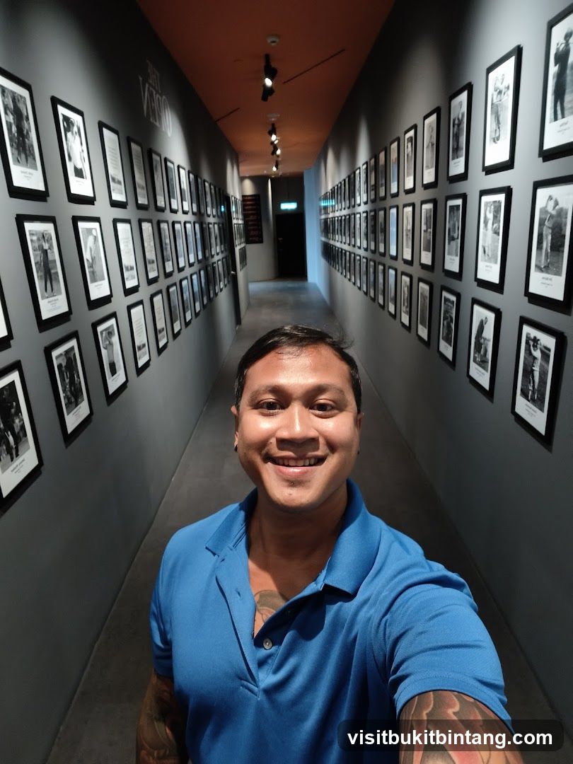 Man in Blue Polo Shirt in Hallway with Framed Photos