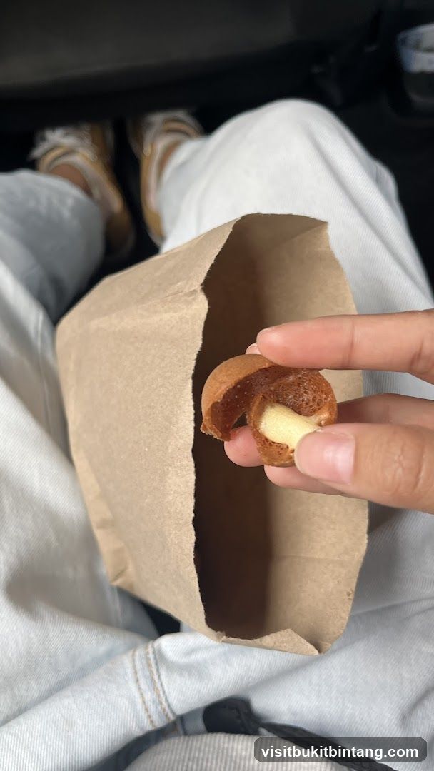 Person holding a pastry from a paper bag