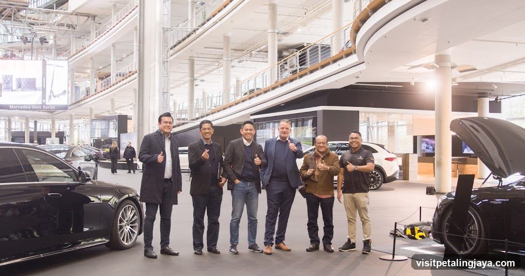 Group of men posing with cars in showroom