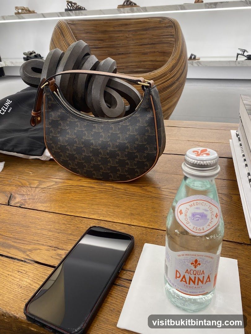 Celine handbag and Acqua Panna water bottle on a wooden table