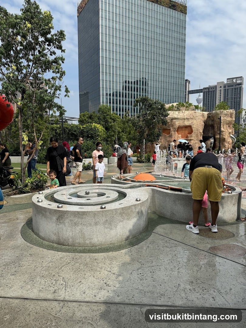 People enjoying a water play area with a skyscraper in the background