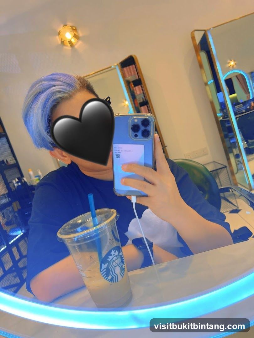 Person with blue-tinted hair taking a selfie in a salon