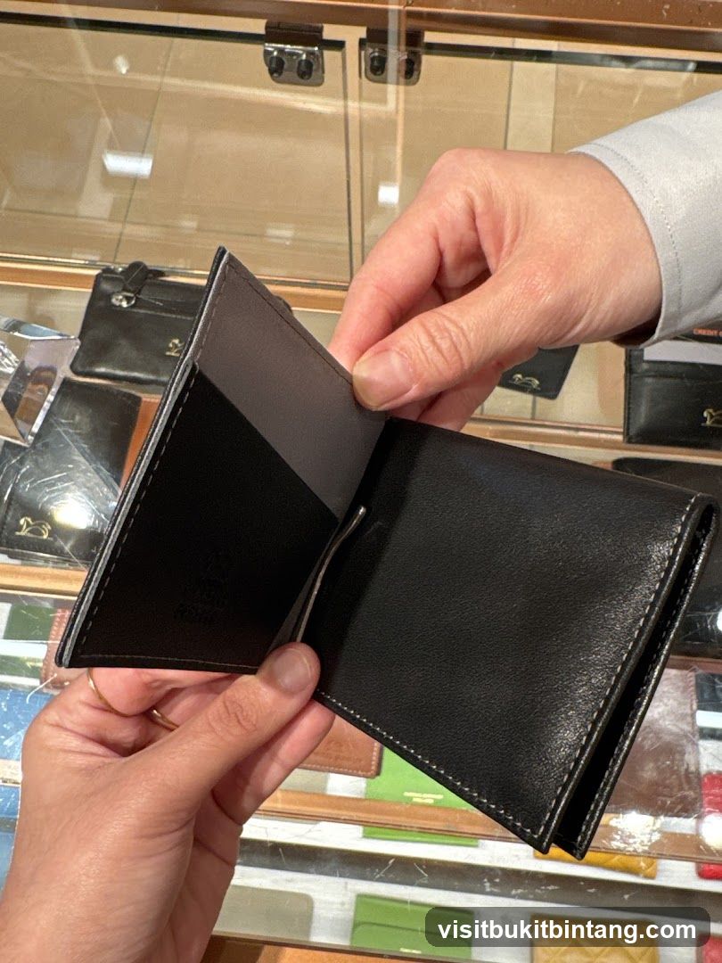 Hands holding a black leather wallet with a money clip