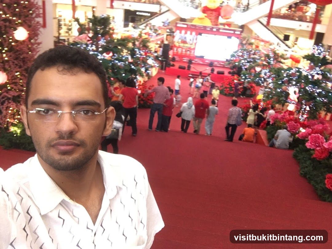 Man taking a selfie in a mall decorated for Christmas
