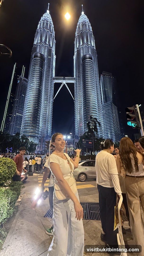 People posing in front of the Petronas Towers at night
