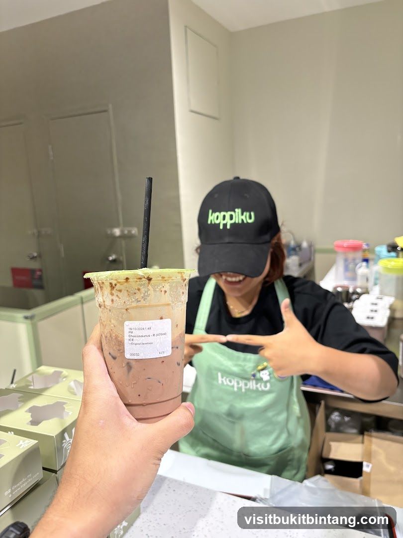 Customer holding a drink with a staff member in the background