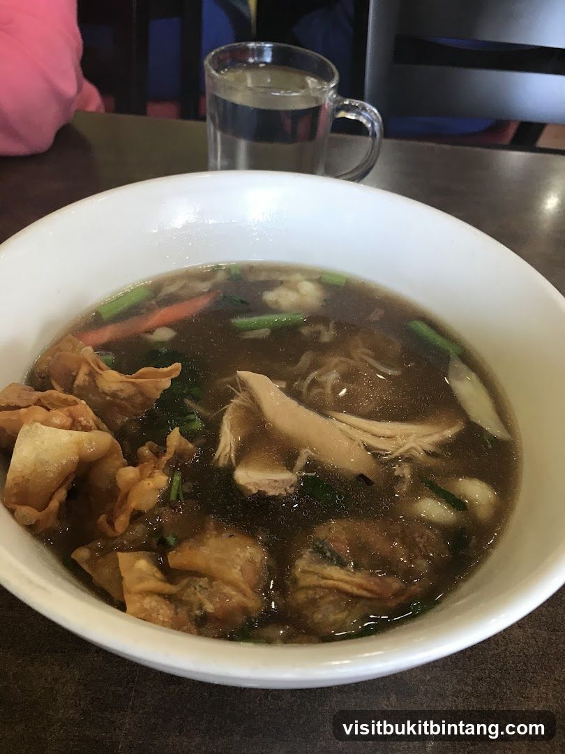 Bowl of noodle soup with wontons and chicken