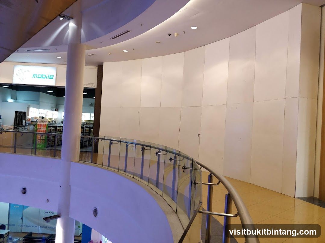 Interior of a shopping mall with a curved railing and a store sign