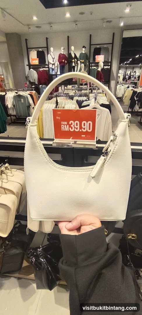 Hand holding a white handbag with a price tag