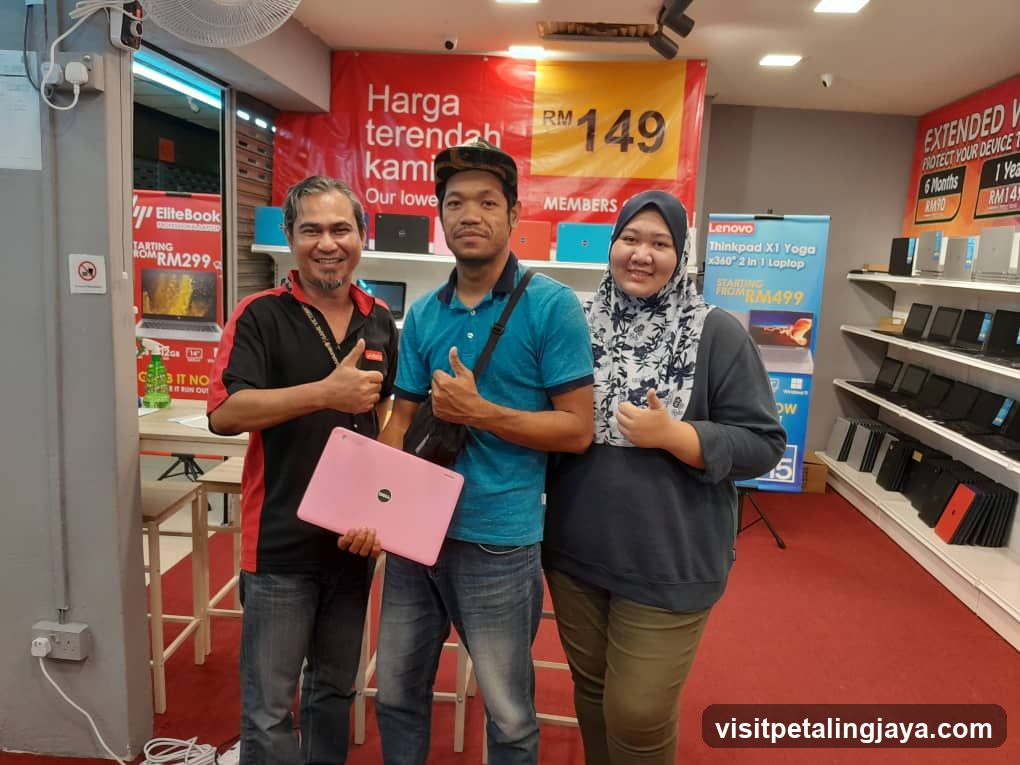 Three people posing with a laptop in a store