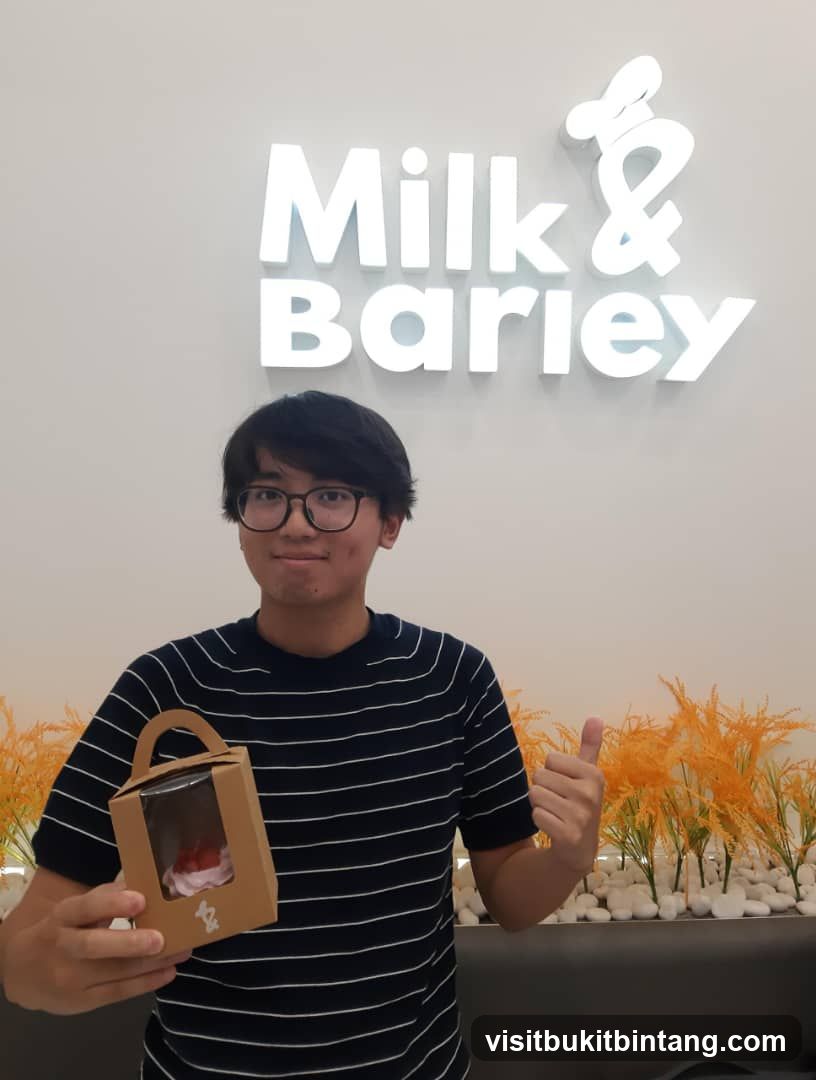Man holding a cupcake with Milk & Barley sign