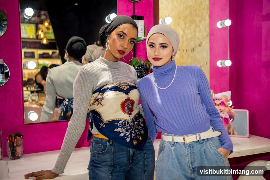 Two women posing in a brightly lit vanity area
