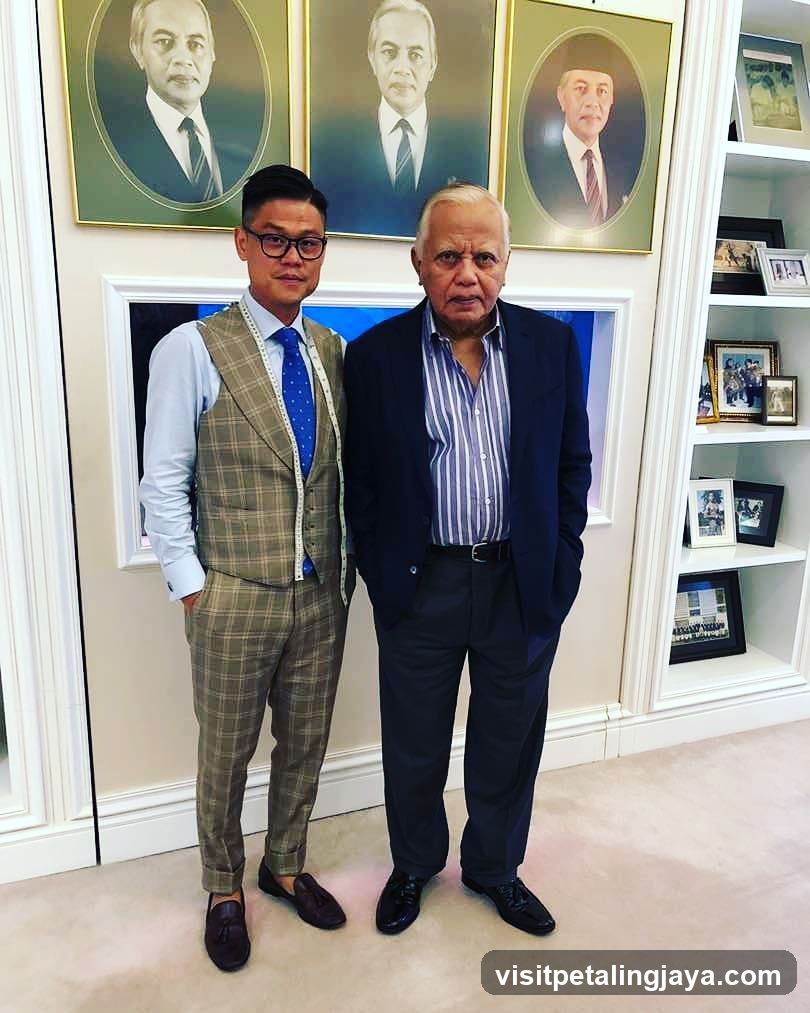Two men posing indoors with framed portraits in background