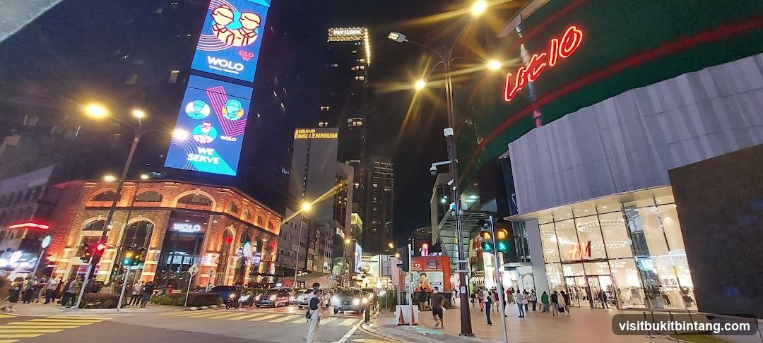 Nighttime street view of a busy urban area with illuminated buildings and traffic.