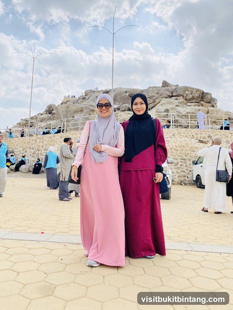 Two women posing in front of a rocky hill
