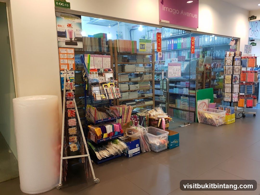 The exterior of a stationery shop with its name "Imago Avenue" displayed above the entrance. The shop is filled with shelves of stationery, books, and other office supplies. There are also displays of cards and gift items outside the entrance.