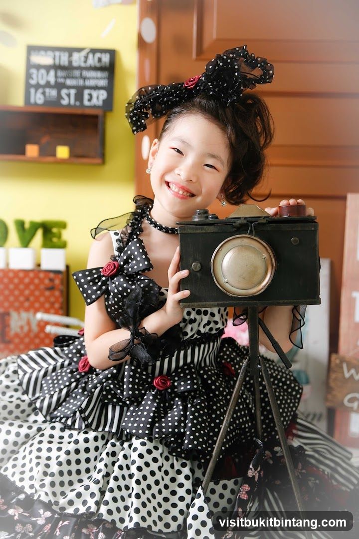 Young girl in a polka dot dress holding a vintage camera
