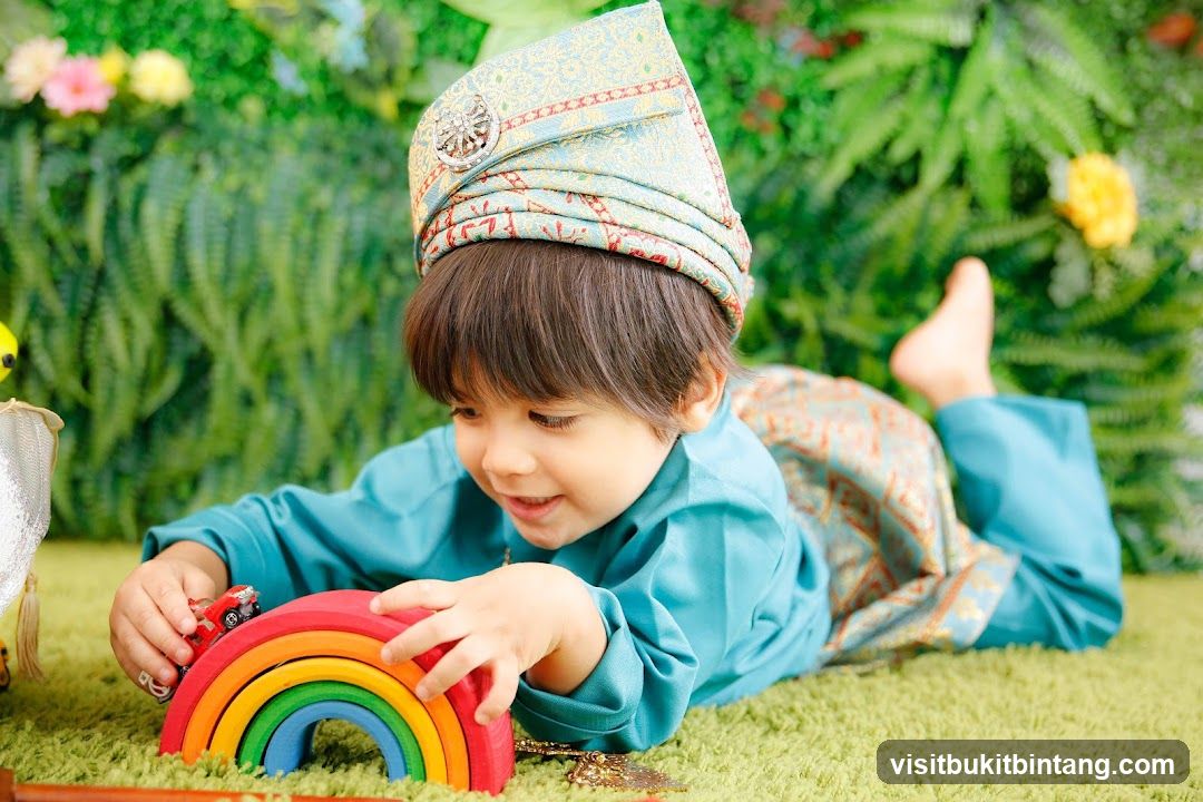 A young boy in traditional attire plays with a rainbow toy.