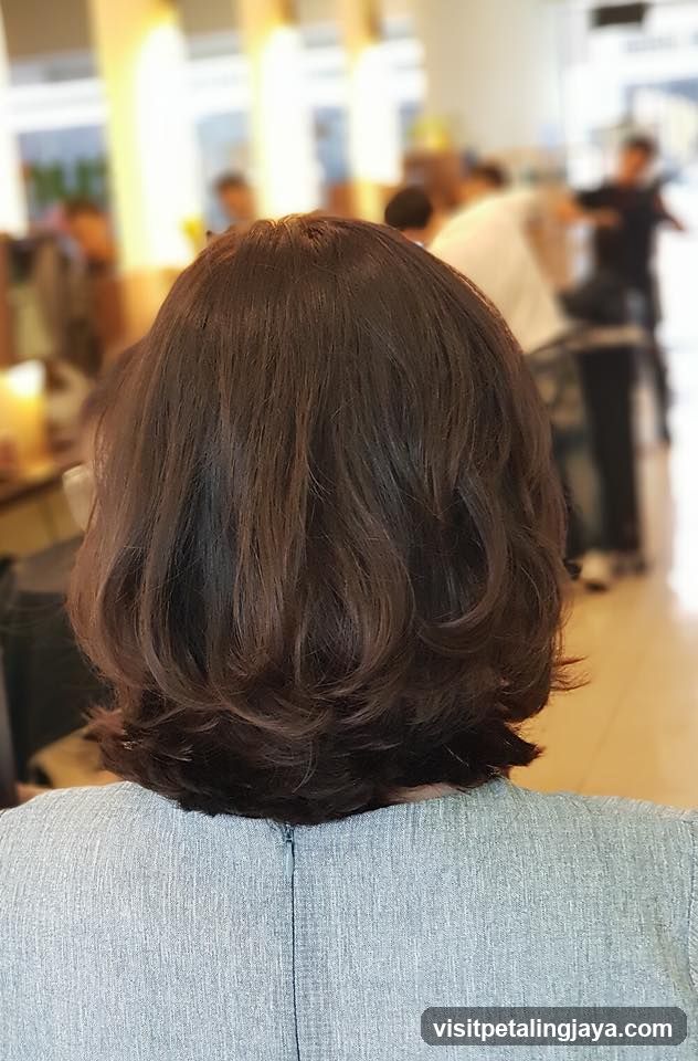 Back of a person with short brown hair in a salon or cafe setting