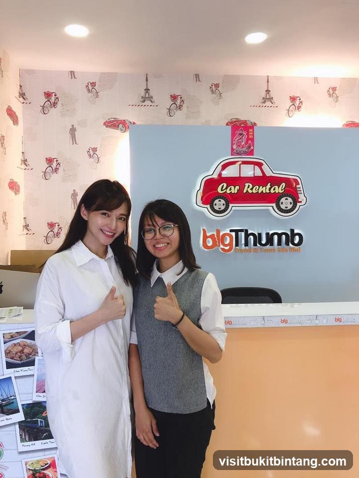 Two women giving thumbs up in front of a car rental sign