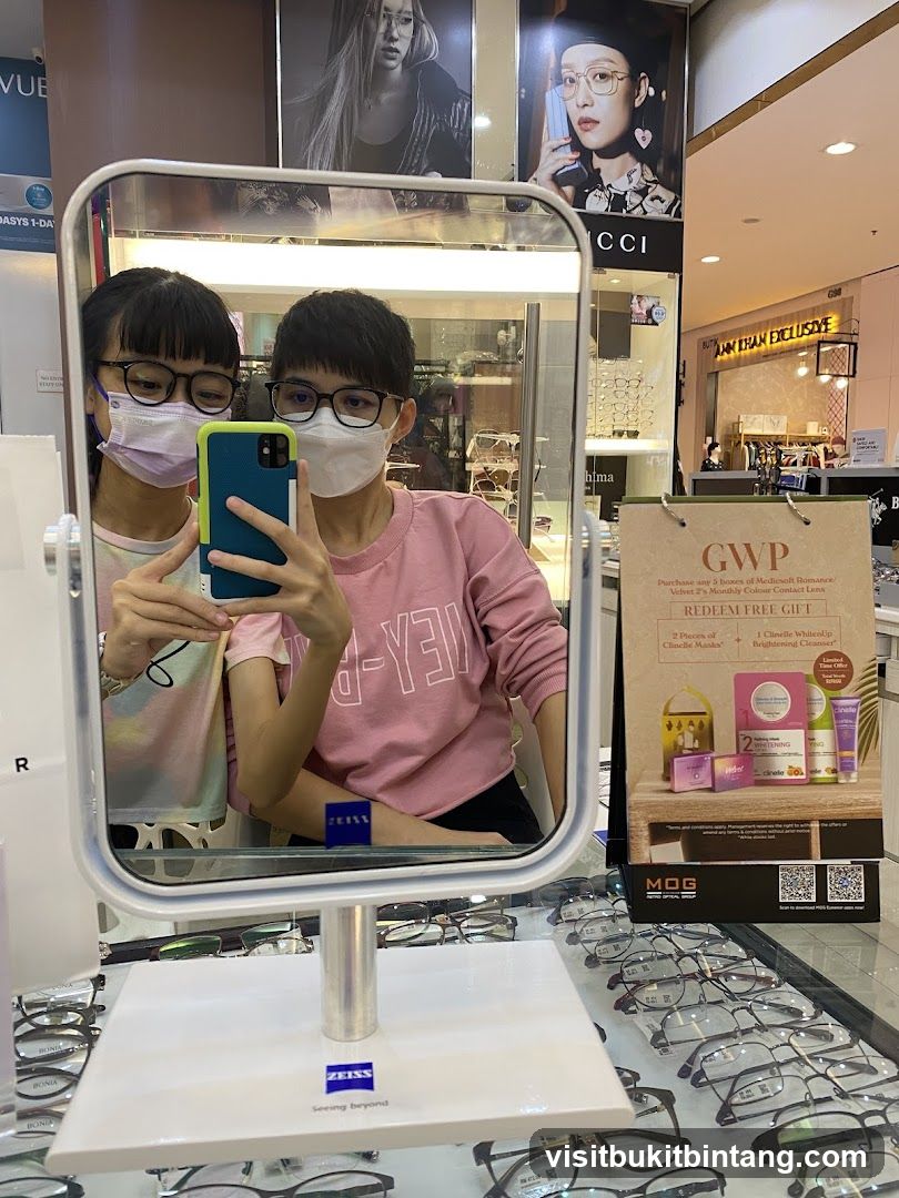 Two people taking a mirror selfie in an optical shop
