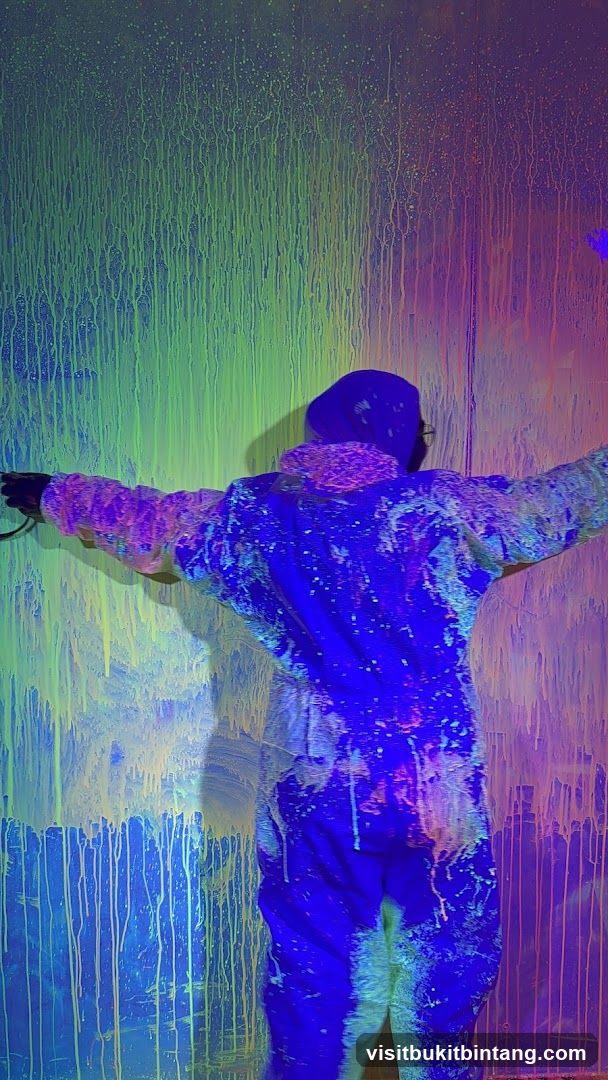 Person in paint-splattered suit in a neon-lit room