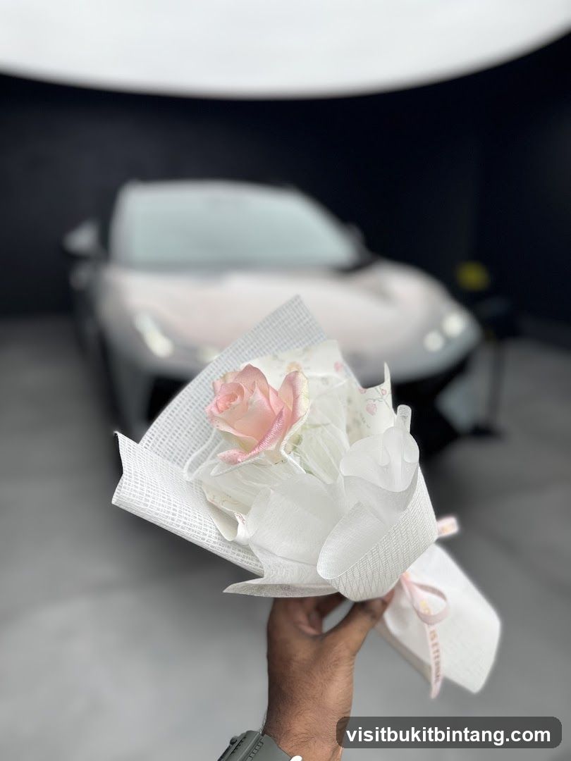 Hand holding a bouquet of flowers in front of a car