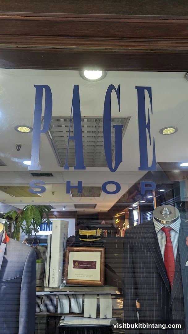 The image shows the storefront window of a shop with the name "RAGE SHOP" displayed in large blue letters. Inside the window, mannequins are dressed in suits, and there are displays of ties and other accessories. A framed certificate, possibly indicating an authorized dealership, is also visible.