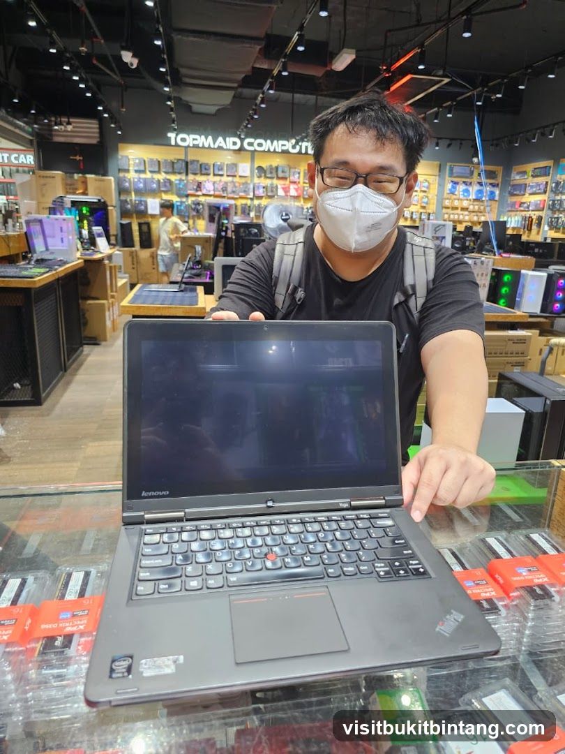 Man holding a laptop in a computer store