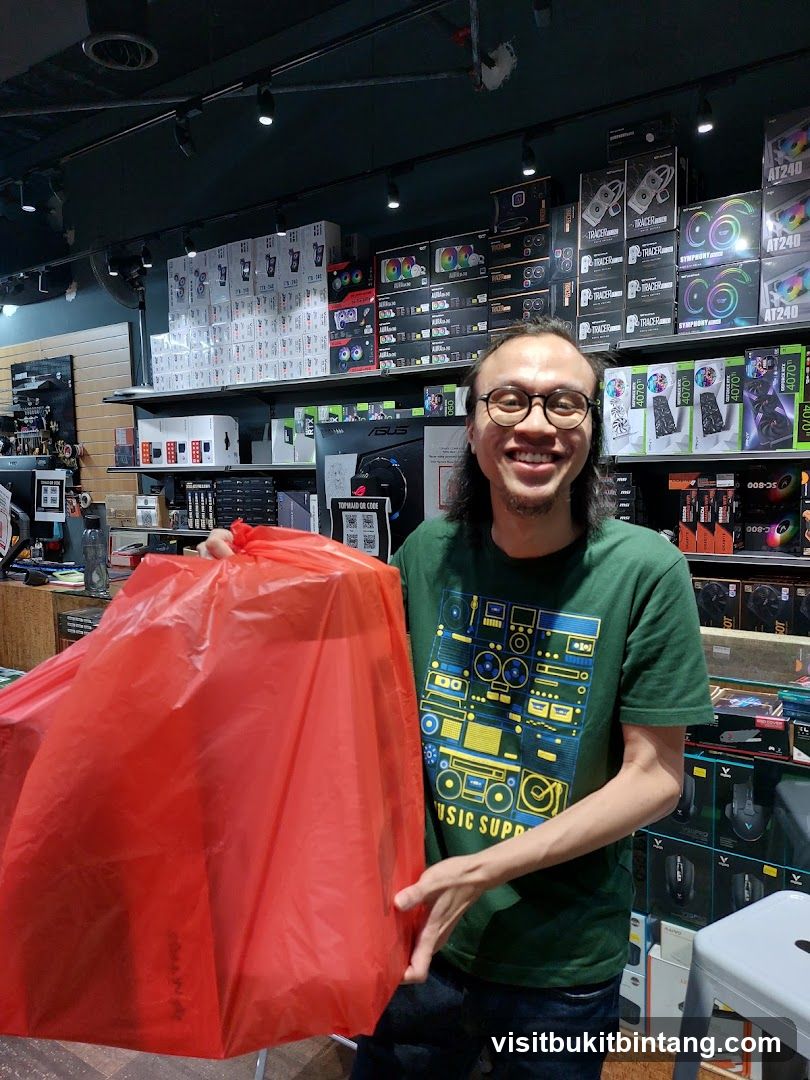 Man holding a red bag in a computer parts store