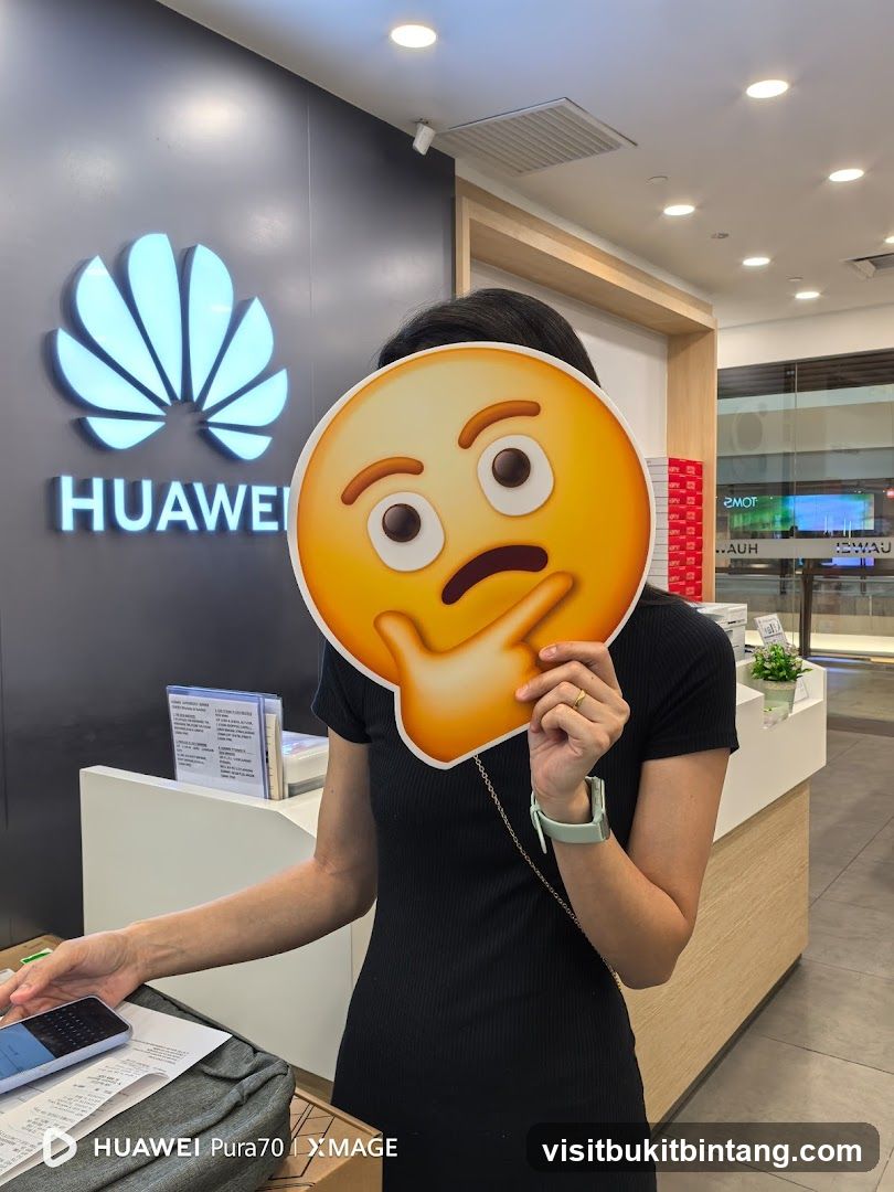 Person holding an emoji mask in front of Huawei logo