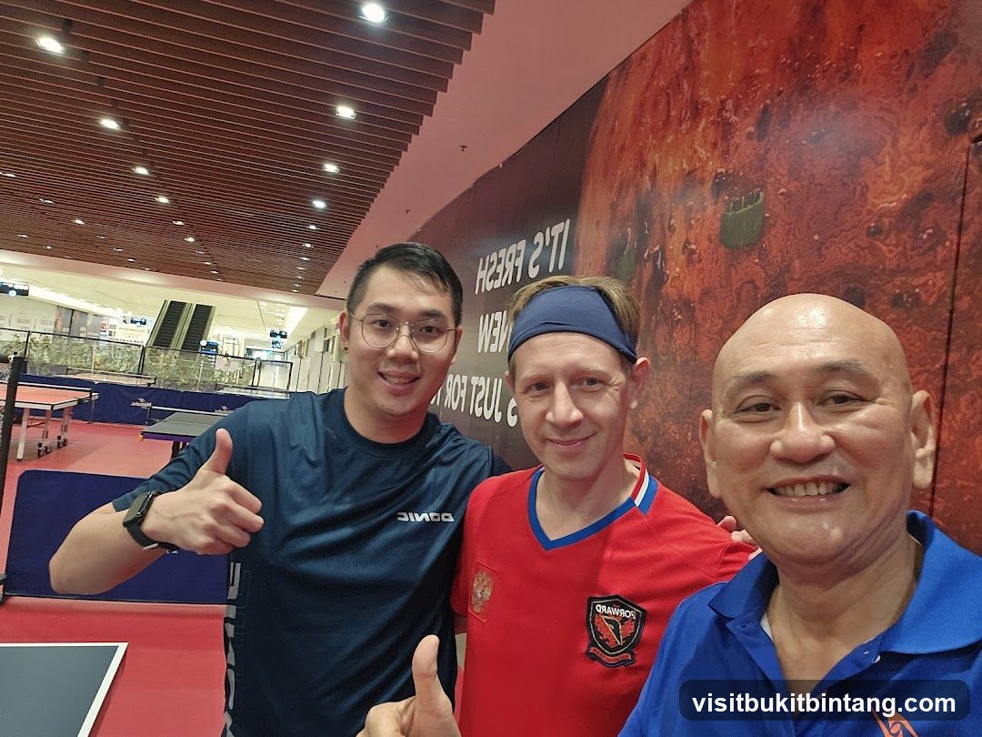 Three men posing for a selfie in a table tennis facility