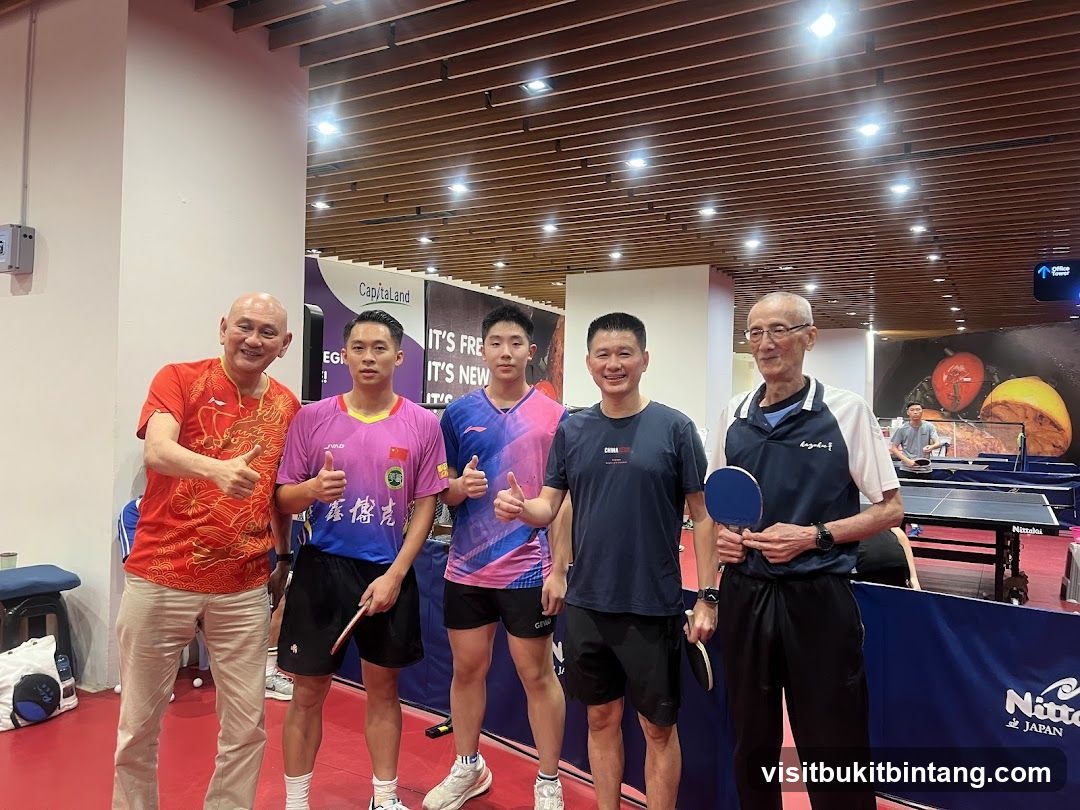 Five men posing for a photo at a table tennis facility