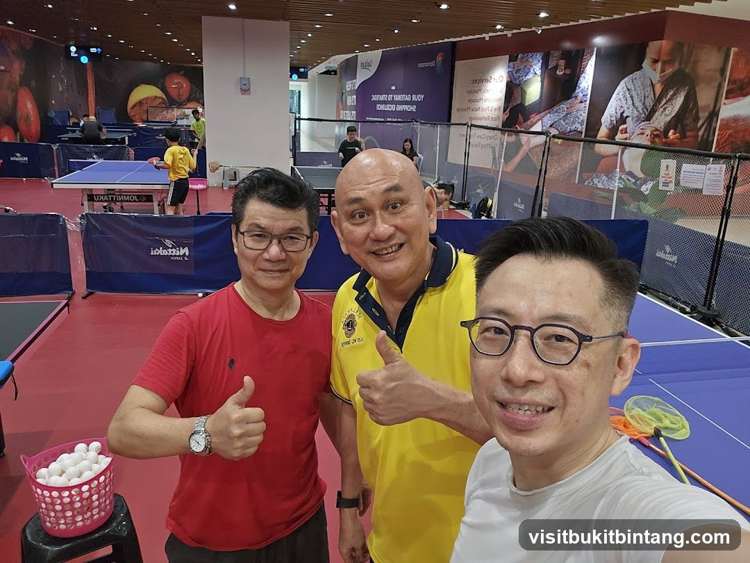 Three men posing for a selfie at a table tennis facility
